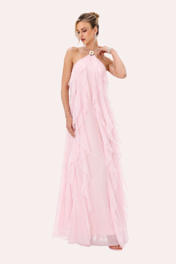A woman modeling a light pink halter-neck maxi dress with a tiered, ruffled tulle skirt, set against a solid off-white background.